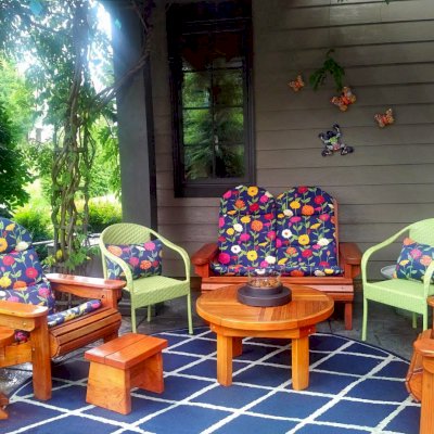 Adirondack Wooden Loveseat (Options: California Redwood, Custom Cushions, Standard Seat Depth, No Ottoman, Transparent Premium Sealant). Photo also shows Round Terrace Table, a Small Wooden Foot Stool, 2 Adirondack Folding Chairs and a Mini 12 inch Round Wood Side Table. Photo Courtesy of Deborah O'Toole of Midlothian, Virginia.