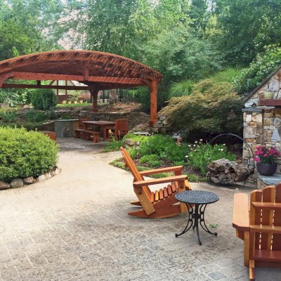 Adirondack Wooden Rocking Chair  (Options: Standard Size, California Redwood, No Cushion, No Ottoman, Transparent Premium Sealant). Photo also shows a Viking Pergola and a San Francisco Patio Table set in the background. Photo Courtesy of Diego B. of Huntsville, AL.  