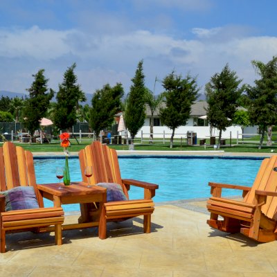 Adirondack Wooden Rocking Chair (Options: Standard Width, Douglas-fir, No Cushion, No Ottoman, Transparent Premium Sealant) and Adirondack Vignette Settee (Options: Standard Width, Redwood, Slightly Rounded Corners, Umbrella Hole, Standard Seat Depth, Custom Cushion, No Ottoman, Transparent Premium Sealant).