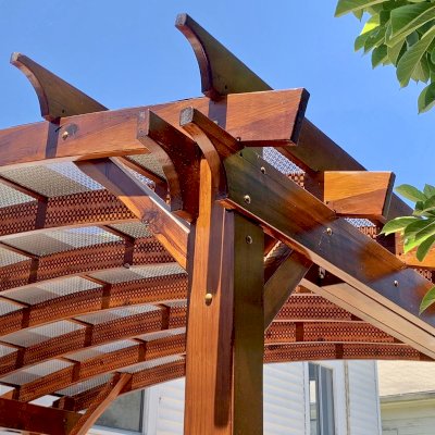 Arched Open Sky Pergolas (Options: 12' L x 14' Arc W, California Redwood, 1 Electrical Wiring Trim, 4-Post Anchor Kit for Concrete, No Ceiling Fan Base, No Privacy Panels, No Curtain Rods, 9.5' Post Height, Transparent Premium Sealant). Custom decorative steel shading added by customer. Photo was taken one year after installation. Photo Courtesy of K. Cates of Oajland, California.
