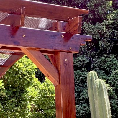 Arched Open Sky Pergolas (Options: 12' L x 14' Arc W, California Redwood, 1 Electrical Wiring Trim, 4-Post Anchor Kit for Concrete, No Ceiling Fan Base, No Privacy Panels, No Curtain Rods, 9.5' Post Height, Transparent Premium Sealant). Custom decorative steel shading added by customer. Photo was taken one year after installation. Photo Courtesy of K. Cates of Oajland, California.