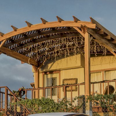 Arched Pergola Kit (Options: 12' L x 16' Arc W, Mosaic Redwood, No Electrical Wiring Trim Kit, 4-Post Anchor Kit for Wood, No Ceiling Fan Bases, No Privacy Panels, No Curtain Rods, 9' Post Height, Transparent Premium Sealant). Free Standing Pergola was altered slightly to place up against house by limiting overhang on house side.
