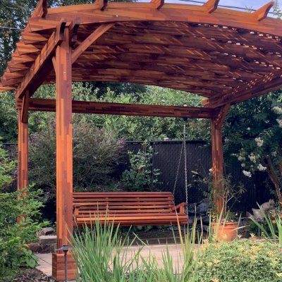 Arched Pergola Kit (Options: 12.5' L x 14' Arc W, Mosaic Redwood, No Electrical Wiring Trim Kit, No Fan Base, No Privacy Panels, Transparent Premium Sealant). Photo Also Shows a XL Bench Swing, Ensenada Style. Photo Courtesy of D. Doty of Bowie, NY.