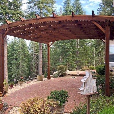 Arched Pergola Kits (Options: 20' L x 18' Arc W, Mature Redwood, No Electrical Wiring Trim, 4-Post Anchor Kit for Stone, No ceiling Fan Base, No Privacy Panels, No Curtain Rods, 10' Post Height, Transparent Premium Sealant). Photo Courtesy of Edward G. of Nevada City, CA. The original fotos for this pergola were from 2012. This photo was taken in Dec 2017 after the pergola was refinished by the Forever Redwood crew by request.