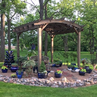 Arched Pergola Kits (Options: 12' L x 14' Arc W, California Redwood, Electrical Wiring Trim for 1 Post, 4-Post Anchor Kit for Concrete, No Ceiling Fan Base, No Privacy Panels, No Curtain Rods, 9' Post Height, Transparent Premium Sealant). Photo Also Shows a Jane's Key West Chair Under the Pergola. Photo Courtesy of  Kay Taylor of Verona, Wisconsin.