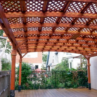 Arched Pergola Kits (Options: 25' L x 20' Arc W, California Redwood, No Electrical Wiring Trim, 6-Post Anchor Kit for Stone, with Ceiling Fan Base, No Privacy Panels, No Curtain Rods, Transparent Premium Sealant). Note: Photo shows roof detail of pergola still under construction (note trim kit boxes set near top of posts and plastic wrap around anchoring hardware at base of posts). Photo Courtesy of Mr. Ami Liani of Brooklyn, NY.