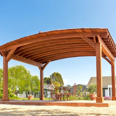 Custom Arched Thick Timber Pavilion (Options: 14' L x 20' Arc W, Mature Redwood, 1 Electrical Wiring Trim, 4-Post Anchor Kit for Concrete, No Ceiling Fan Base, No Privacy Panel, No Curtain Rods, 9 ft H, with 2x6's Roof Boards by Custom Request, Coffee-Stain Premium Sealant). Photo Courtesy of Siino Ventures of Kikrland, Washington.