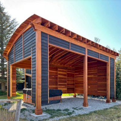 Custom  Arched Thick Timber Pavilion (Options: 28' L x 18' Arc W, California Redwood, Post Anchor Kit for High-Wind, with Custom Privacy Walls, 10' & 12' H Posts, No Curtain Rods, Walls Siding with Black Stain and the Rest of the Structure with Transparent Premium Sealant). Photo Courtesy of D. Harris of Tetonia, ID.