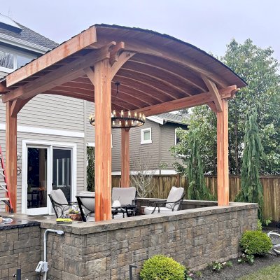  Arched Thick Timber Pavilion (Options: 14' L x 14' Arc W, Mosaic Douglas-fir, 2 Electrical Wiring Trims, 4-Post Anchor Kit for High-Wind, 1 Ceiling Fan Base, 11' H Posts, No Privacy Panel, No Curtain Rods, 12 ft H, No Decorative Trims on Posts, Unfinished). Photo Taken Before Gutters Were Installed. Photo Courtesy of K. Bachman-Ellis of Bellevue, WA.
