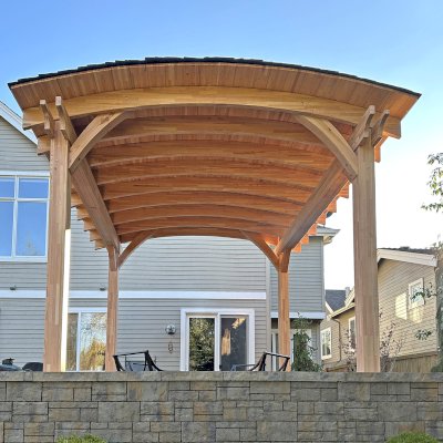 Arched Thick Timber Pavilion (Options: 14' L x 14' Arc W, Mosaic Douglas-fir, 2 Electrical Wiring Trims, 4-Post Anchor Kit for High-Wind, 1 Ceiling Fan Base, 11' H Posts, No Privacy Panel, No Curtain Rods, 12 ft H, No Decorative Trims on Posts, Unfinished). Photo Courtesy of K. Bachman-Ellis of Bellevue, WA.