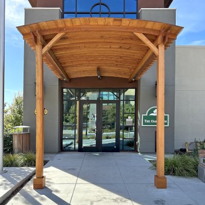 Custom  Arched Thick Timber Pavilion (Options: 10' L x 12' Arc W, Douglas-fir, 2-Post Anchor Kit for Concrete, No Ceiling Fan Base, 11'-5" H Posts, No Privacy Panel, No Curtain Rods, No Decorative Trims on Posts, Transparent Premium Sealant). Pavilion attached as an extension of an existing 5' L roof. Photo Courtesy of R. Cole of Fairfield, CA.