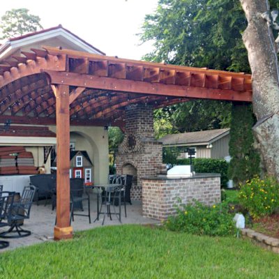 Custom Attached Arched Pergola Kits (Options: 22' L x 26' W, California Redwood, No Electrical Wiring Trim, Rafters at 18" and Slats at 18", 3-Post Anchor Kit for High-Wind, with Transparent Rain Guard, Ceiling Fan Base, No Privacy Panels, No Curtain Rods, 10' Post Height, Transparent Premium Sealant, Attached to Wall by Support Side, Arches are 2x12's by Custom Request). Photo Courtesy of M. Yocco of Hilton Head, South Carolina.