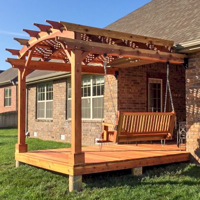 Attached Arched Pergola Kits (Options: 10' x 10', California Redwood, No Electrical Wiring Trim, with Lattice Panels, 2-Post Anchor Kit for Concrete, No Ceiling Fan Base, No Privacy Options, No Curtain Rods, 9ft H, Transparent Premium Sealant) with Deck and Bench Swing by Custom Request. Photo Courtesy of Telory of A. of Springfield, MO.. 