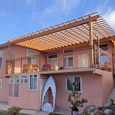 Attached Garden Pergolas (Options: 27' 11" L x 17' 4" W, Attached to House Eave by Rafters Side, Douglas-fir, No Electrical Wiring Trim, Rafters at 18, slats at 12, Transparent Premium Sealant). Extra posts against the house, Pergola attached to the house eave. Photo Courtesy of R. Hernandez of Ensenada, Mexico.