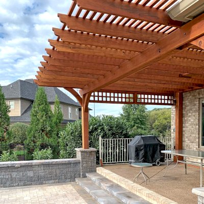 Custom Attached Garden Pergola (Options: 21' x 18', Mature Redwood, 1 Custom Lattice Privacy Panel, 1 Ceiling Fan Base, Transparent Premium Sealant). This customized attached pergola was built to fit around a low roof with an extended overhang and posts up against the house to meet the customer's vision perfectly. Photo Courtesy of B. McAdams of Farragut, Tennessee.
