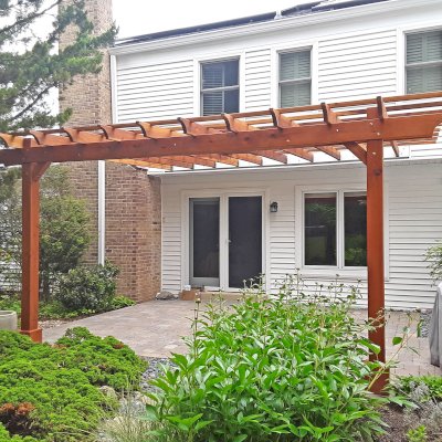 Attached Garden Perglola (Options: 18' x 15', California Redwood, Open Roof with Slats at 18", Rafters at 18", Attached to the Wall by Support Side, 2-Post Anchor Kit for Concrete, 1 Ceiling Fan Base, Transparent Premium Sealant). Custom framed 2' x 2' Polycarbonate Rain Guard Centered Atop Ceiling Fan Base to Protect Fan From Moisture. Photo Courtesy of M. Holland of Potomac, Maryland.
