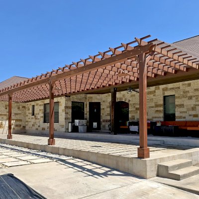 Custom Attached Garden Pergola (Options: 53' x 12', California Redwood, Open Roof with Slats at 12", Rafters at 18", 3-Post Anchor Kit for Concrete, 3 Ceiling Fan Bases, Coffee-Stain Premium Sealant). Ledger Board Attached to Wood House Fascia on 53' Side, and Steel Plate Used to Attach Dual Supports to Masonry House Wall. Photo Courtesy of S. Slawson of Buda, Texas.