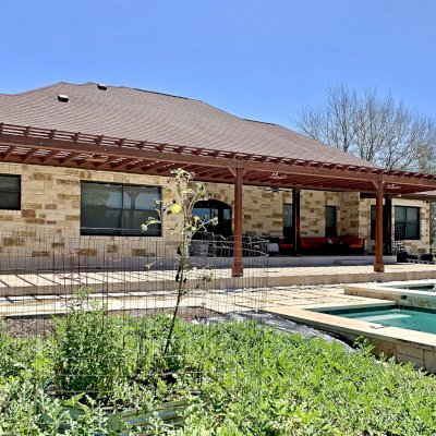 Custom Attached Garden Pergola (Options: 53' x 12', California Redwood, Open Roof with Slats at 12", Rafters at 18", 3-Post Anchor Kit for Concrete, 3 Ceiling Fan Bases, Coffee-Stain Premium Sealant). Ledger Board Attached to Wood House Fascia on 53' Side, and Steel Plate Used to Attach Dual Supports to Masonry House Wall. Photo Courtesy of S. Slawson of Buda, Texas.