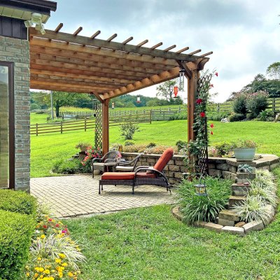 Attached Garden Perglola (Options: 18' x 12', California Redwood, Open Roof with Slats at 12", Rafters at 18", Attached to the Wall by Support Side, 2-Post Anchor Kit for Concrete, No Privacy Panel, No Ceiling Fan Base, Transparent Premium Sealant). Photo Taken 1 Year After Installation. Photo Courtesy of C. Nichols of Clinton, TN.