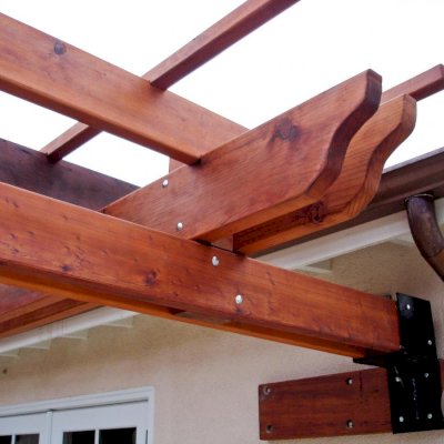 Some attached pergolas cannot be secured with a ledger board. In some instances, we build custom steel anchors to get the job done like shown here. Photo also highlights the extensive notching and finishing work that goes into each timber of our Kits.