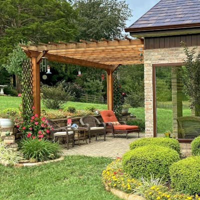 Attached Garden Perglola (Options: 18' x 12', California Redwood, Open Roof with Slats at 12", Rafters at 18", Attached to the Wall by Support Side, 2-Post Anchor Kit for Concrete, No Privacy Panel, No Ceiling Fan Base, Transparent Premium Sealant). Photo Taken 1 Year After Installation. Photo Courtesy of C. Nichols of Clinton, TN.