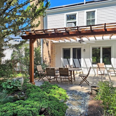 Attached Garden Pergola (Options: 18' x 15', California Redwood, Open Roof with Slats at 18", Rafters at 18", 2-Post Anchor Kit for Concrete, 1 Ceiling Fan Base, Transparent Premium Sealant). Custom framed 2' x 2' Polycarbonate Rain Guard centered atop ceiling fan base to protect fan from moisture. Photo Taken 6 Months After Installation. Photo Courtesy of M. Holland of Potomac, Maryland.