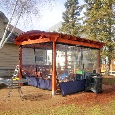 Custom Backyard Pavilion Kit with Extra Supports and Braces on Arches Side (Options: 16' L x 12' Arc W, Douglas-fir, 1 Post Electrical Wiring Trim, 4-Post Anchor Kit for High-Wind, 1 TV Mount Base by Custom Request, No Privacy Panels, No Curtain Rods, 9 ft Post Height, Cherry-Stain Premium Sealant). Photo Courtesy of E. Chen of Ann Arbor, Michigan.