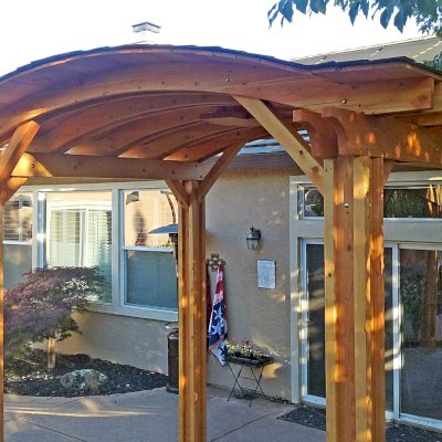 Backyard Pavilion Kits (Options: 12' L x 10' Arc W, Douglas-fir, 1 Post Electrical Wiring Trim, 4-Post Anchor Kit for Concrete, Add Ceiling Fan Base, No Privacy Panels, No Curtain Rods, 9 ft Post Height, Transparent Premium Sealant). Photo Courtesy of R. Short of Roseville, CA.