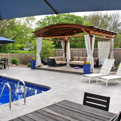 Backyard Pavilion Kits (Options: 15' L x 18' Arc W, California Redwood, 2 Post Electrical Wiring Trims, 4-Post Anchor Kit for Concrete, 1 Ceiling Fan Base, No Privacy Panels, 4 Curtain Rods, 9 ft Post Height, Transparent Premium Sealant). Photo Courtesy of S. McDonald of Lake Barrington, Illinois.