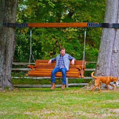 Bench Swings (Seats Only) (Options: XL Garden Bench, California Redwood, Ensenada Seat Design, Custom Engraving, Custom Heavy Duty Hinged Steel Harnesses with a 6x6 Beam, Transparent Premium Sealant). Custom Tree Rings and Beam Designed by Forever Redwood to Attach Swing to the 2 Trees. Photo Courtesy of P. Scaturro of Bedford, New York.