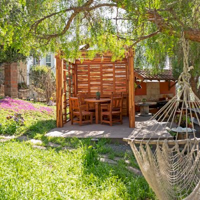 Catalina Island Pergola (Options: 8' x 8', Mosaic Redwood, 8' Post Height, Transparent Premium Sealant). Photo Also Shows a Round Patio Table with Segovia Chairs.