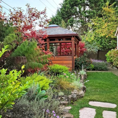 Custom Wood Pavilion Kit (Options: 18' x 14', California Redwood, with Deck, Fixed Wall on Rear Side, Half Walls on Sides, and Custom Railings on Front Side, Transparent Premium Sealant). Photo Courtesy of S. Peletta of Half Moon Bay, CA.