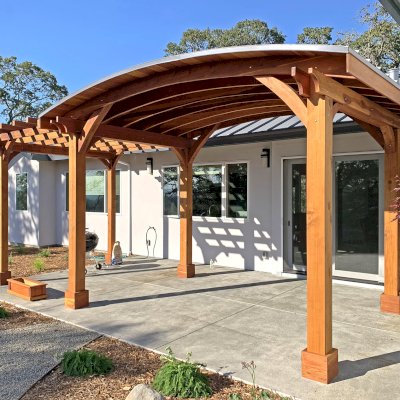 Custom Wood Pavilion Kit with Attached Custom Garden Pergola (Options: 11' L x 16' Arc W [Garden Pergola is 11' L x 8' W], California Redwood, No Post Electrical Wiring Trim, 6-Post Anchor Kit for Concrete, No Ceiling Fan Bases, No Privacy Panels, No Curtain Rods, 10 ft Post Height, Transparent Premium Sealant). Photo Courtesy of K. Jaraczewski of Larkfield-Wikiup, CA.