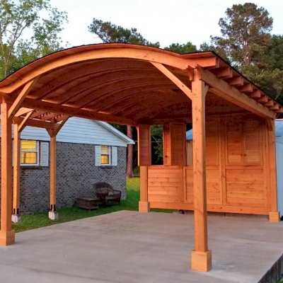 Custom Wood Pavilion Kits (Options: 20' L, 14' W, 1 Shutter Privacy Panel, Douglas-fir, No Electrical Wiring Trim, 2-Post Anchor Kit for Concrete, No Ceiling Fan Base, No Curtain Rods, 9.5' Post Height, Transparent Premium Sealant) with an Attached Arched Pergola on the Left. Photo Courtesy of E.West of Pine Hill, AL.