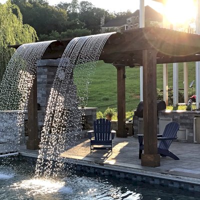 Custom Garden Pergola (Options: 16' L x 16' W, California Redwood, 4-Post Anchor Kit for Concrete, Cherry Stain Premium Sealant). Plumbing was built into the timbers to create a waterfall. Photo Courtesy of D. Hogan of Charlottesville, Virginia.