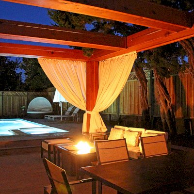 Custom Wooden Fat Timber Pergola (Options: 20' L, 16' W, Old-Growth Redwood, 4 Electrical Wiring Trims, with 2 3/4" x 11 1/4" Roof Timbers and 11 1/4" x 11 1/4" Posts, 4-Post Anchor Kit for High-Wind, No Privacy Panels, Curtain Rods on 4 sides, 10' Post Height, Transparent Premium Sealant). Retractable Canopy designed in cooperation with Infinity Canopy of Los Angeles, CA (www.infinitycanopy.com). Once you have your design finalized, you can forward your drawings to Infinity to add the perfect retractable canopy solution for maximum shade versatility! Photo Courtesy of Darren & Elva Linscott of San Jose, CA.