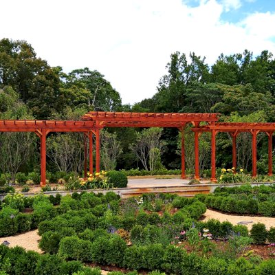 Custom Wooden Pergola (Options: 56' L [20' W in Central Section and 8' W on Sides], Mature Redwood, No Electrical Wiring Trim, 14-Post Anchor Kit for Concrete, No Ceiling Fan Base, No Privacy Panels, No Curtain Rods, Transparent Premium Sealant). Photo Courtesy of J. Kelly of Crozet, Virginia.
