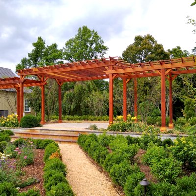 Custom Wooden Pergola (Options: 56' L [20' W in Central Section and 8' W on Sides], Mature Redwood, No Electrical Wiring Trim, 14-Post Anchor Kit for Concrete, No Ceiling Fan Base, No Privacy Panels, No Curtain Rods, Transparent Premium Sealant). Photo Courtesy of J. Kelly of Crozet, Virginia.