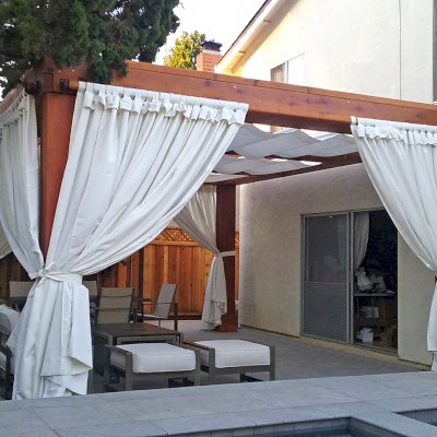 Custom Wooden Fat Timber Pergola (Options: 20' L, 16' W, Old-Growth Redwood, 4 Electrical Wiring Trims, with 2 3/4" x 11 1/4" Roof Timbers and 11 1/4" x 11 1/4" Posts, 4-Post Anchor Kit for High-Wind, No Privacy Panels, Curtain Rods on 4 sides, 10' Post Height, Transparent Premium Sealant). Retractable Canopy designed in cooperation with Infinity Canopy of Los Angeles, CA (www.infinitycanopy.com). Once you have your design finalized, you can forward your drawings to Infinity to add the perfect retractable canopy solution for maximum shade versatility! Photo Courtesy of Darren & Elva Linscott of San Jose, CA.