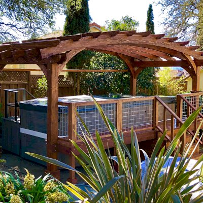 Custom Arched Pergola Kits (Options: 12' L x 22' Arc W, Douglas-fir, Unattached, Electrical Wiring Trim Kit for 1 Post, Arched Roof with Lattice Panels and Acrylic Sheets Centered, 4-Post Anchor Kit for Stone, with 8 x 8 Posts by Custom Request, No Ceiling Fan Base, No Privacy Panels, 1 Curtain Rod, 9' Post Height, Coffee-Stain Premium Sealant) with Custom Deck and Stairs by Custom Request. Photo Courtesy of Steve & Heidi Jones of Windsor, CA.