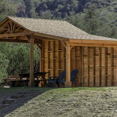 Custom Del Norte Outdoor Kitchen Pavilion (Options: 12' L x 12' W, with 9' x 12' Shed Pavilion Attached, Douglas-fir, 6-Post Anchor Kit for High-Wind, No Ceiling Fan Base, No Electrical Wiring Trim Kit, No Post Decorative Trims, with Custom Solid Wall, Transparent Premium Sealant). Photo Courtesy of J. Randall of Warner Springs, CA.