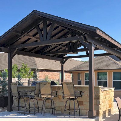 Del Norte Outdoor Kitchen Pavilion (Options: 20' L x 16' W, Mosaic Redwood, 4-Post Anchor Kit for Concrete, 10.5' H Posts, 1 Ceiling Fan Base, 2 Fascia Boards, Custom Sealant [Cordovan Brown Solid Color]). Photo Courtesy of S. Oster of Round Rock, Texas.