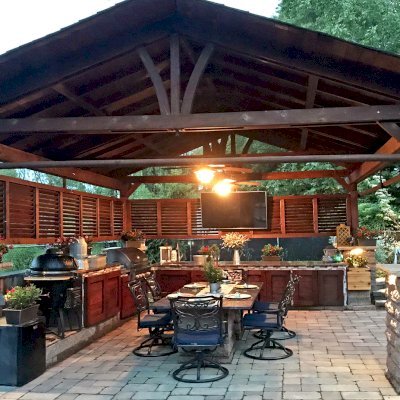 Del Norte Outdoor Kitchen Pavilion (Options: 20' L x 18' W, Mature Redwood, 4-Post Kit for High-Wind, 2 Ceiling Fan Bases, 2 Electrical Wiring Trim Kits, 2 Sets of Louvers on 2 Sides, No Post Decorative Trims, 9' H Posts Wrapped in Stone After Installation, Coffee-Stain Premium Sealant). Photo Courtesy of Shawn and Marilyn Murray of Walden, New York.