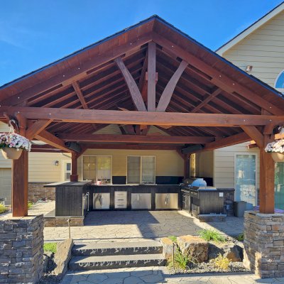 Del Norte Outdoor Kitchen Pavilion (Options: 19.5' L x 17' W, Mature Redwood, No Privacy Panel, Post Anchor Kit for High Wind, 10.5' H Posts, 1 Ceiling Fan Base, Electrical Wiring Trim for 2 Posts, No Curtain Rod, Coffee-Stain Premium Sealant). Photo Courtesy of Elements Landscaping of Hayden, ID.