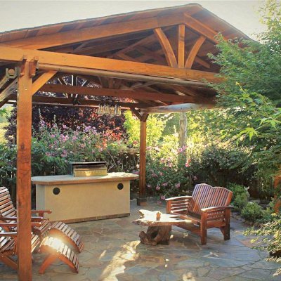 Del Norte Outdoor Kitchen Pavilion (Options: 16' L x 19' W, California Redwood, 4-Post Anchor Kit for Concrete, 4 Curtain Rods, No Ceiling Fan Base, Electrical Wiring Trim Kit for 2 Posts, Transparent Premium Sealant). Photo also shows a Loveseat and two Ensenada Easychairs with Ottoman. Photo Courtesy of D. Leetz of Petaluma, CA.