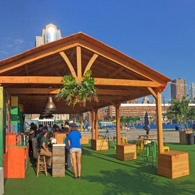 Rio on the Hudson: Olympic Village in NYC. 2 Del Norte Outdoor Kitchen Pavilions (Options: 25' L x 20' W, Douglas-fir, We used 2' x 2' x 2'  Concrete Blocks to Anchor the Structure Because it is a Temporary Installation, Covered the Concrete Blocks with Wooden Boxes, No Ceiling Fan Base, Transparent Premium Sealant). Photo Courtesy of A. Fisher of New York, NY.