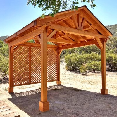 Del Norte Outdoor Kitchen Pavilion (Options: 12' L x 12' W, 1 Full Wall Lattice Privacy Panel, Douglas-fir, 4-Post Anchor Kit for High-Wind, No Ceiling Fan Base, No Electrical Wiring Trim Kit, Straight Internal Truss Supports by Custom Request, No Post Decorative Trims, Transparent Premium Sealant). Photo Courtesy of J. Randall of Warner Springs, CA.