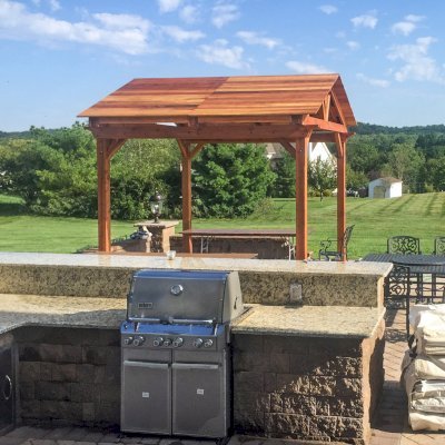 Del Norte Outdoor Kitchen Pavilion (Options: 12' L x 12' W, California Redwood, Unattached, 4-Post Anchor Kit for Concrete, Electrical Wiring Trim for 1 Post, 9' Posts, No Ceiling Fan Base, No Privacy Panels, No Curtain Rods, Transparent Premium Sealant). Photo Courtesy of Manjit Guleria of Pennington, NJ.