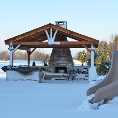 Del Norte Outdoor Kitchen Pavilion (Options: 20' L x 20' W, California Redwood, 4-Post Anchor Kit for High-Wind, 1 Ceiling Fan Base, Transparent Premium Sealant, Custom Cut Out in the Back Overhang to Fit the Fireplace). Photo Courtesy of Tom Mislenkov of Chesterton, Indiana.
