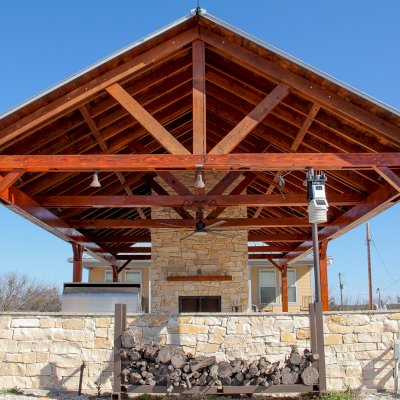 Del Rio Cathedral Ceiling Thick Timber Pavilion (Options: 42' L x 22' Triangle Base W, No Privacy Panels, Mature Redwood, 10' ft Height, Electrical Wiring Trim for 1 Post, 6-Post Anchor Kit for High-Wind, No Post Decorative Trim, 2 Ceiling Fan Bases, No Curtain Rods, Transparent Premium Sealant). Note: Fireplace and kitchen counter was added after the Pavilion was installed by a Mason.  Forever Redwood does not do masonry work, but our designs can incorporate them.
